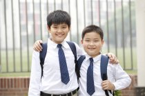 Compañeros alegres en uniforme escolar en la calle - foto de stock