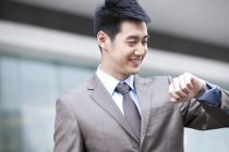 Chinese businessman looking at wristwatch on street — Stock Photo