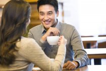 Cinese coppia chatta in caffè con tazza di caffè — Foto stock