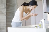 Mujer china lavando la cara en el baño - foto de stock