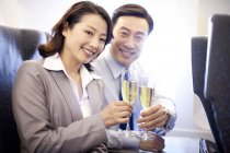 Chinesische Geschäftsleute stoßen im Flugzeug mit Champagner an — Stockfoto