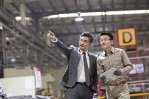 Geschäftsmann und Ingenieur nutzen digitales Tablet und sprechen in der Fabrik — Stockfoto