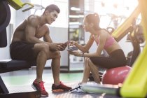 Chinese couple resting at gym and using smartphones — Stock Photo