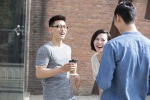 Amigos chinos hablando y riendo con café en la calle - foto de stock