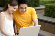 Chinese couple using laptop outdoors — Stock Photo