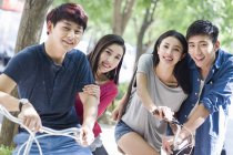 Chinese friends sitting on bicycles on street — Stock Photo