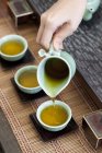 Primo piano della mano femminile che versa il tè nelle tazze da tè — Foto stock