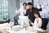 Зрілою людиною і китайський архітекторів cheering в офісі — стокове фото