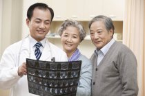 Chinese doctor showing x-ray test result to senior couple — Stock Photo