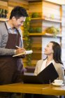 Китайський офіціант приймати замовлення від жінки в ресторані — стокове фото