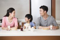 Familia china desayunando en la cocina - foto de stock