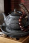 Китайский чайник и молитвенные бусы на деревянном подносе — стоковое фото