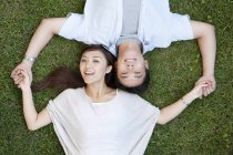 Overhead view of young Chinese couple lying on grass — Stock Photo