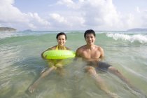 Молода пара плаває з надувним кільцем у морській воді — стокове фото