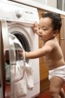 Chinese infant putting laundry in washing machine — Stock Photo