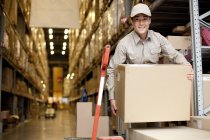 Male Chinese warehouse worker carrying boxes — Stock Photo