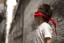 Хлопчик з з зав'язаними очима грають приховати в хованки в алея — стокове фото
