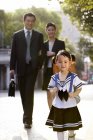 Chinese parents walking with schoolgirl on street — Stock Photo