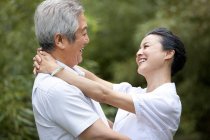 Chinese senior couple hugging each other outdoors — Stock Photo