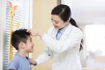 Médecin chinois mesurant la taille du garçon — Photo de stock