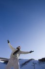 Chinese man with arms outstretched at ski resort — Stock Photo