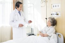 Chinese doctor talking with patient in hospital — Stock Photo