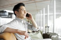 Chinese man talking on phone at airport building — Stock Photo