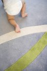 Infant legs on carpet with lined pattern — Stock Photo