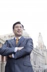 Portrait of Chinese businessman with arms crossed in city — Stock Photo