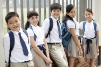 Scolari cinesi in uniforme scolastica appoggiato contro recinzione — Foto stock