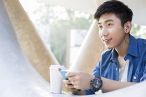 Китаец слушает музыку со смартфона и держит кофе — стоковое фото