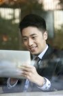 Hombre de negocios chino usando tableta digital en la cafetería - foto de stock