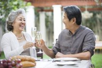 Senior Chinese couple clinking champagne flutes — Stock Photo