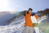 Chinesin posiert mit Snowboard im Skigebiet — Stockfoto