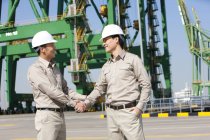 Male Chinese shipping industry workers shaking hands — Stock Photo