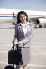 Chinesische Geschäftsfrau mit Gepäck auf dem Rollfeld eines Flugzeugs — Stockfoto