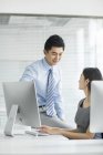 Chinese businesswoman and businessman talking in office — Stock Photo