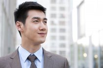 Porträt eines jungen chinesischen Geschäftsmannes, der in der Stadt wegschaut — Stockfoto