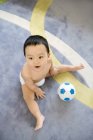 Infante chino jugando con pelota de fútbol - foto de stock