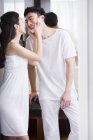 Chinese woman rubbing shaving cream over male face — Stock Photo