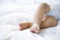 Primer plano de los pies del bebé en la cama - foto de stock