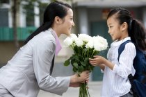 China colegiala ofreciendo madre ramo de flores - foto de stock
