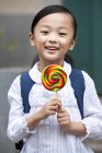 Chinese schoolgirl holding lollipop on street — Stock Photo