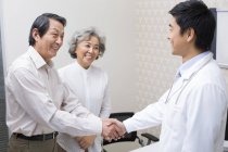 Китайская пара пожимает руку доктору в больнице — стоковое фото