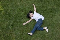Extático menina chinesa deitada na grama verde — Fotografia de Stock