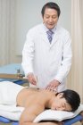 Médico chino senior que da terapia de moxibustión al paciente masculino - foto de stock