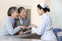 Chinese nurse helping senior couple at nurse station — Stock Photo