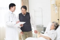 Китайский врач разговаривает со старшей парой в больнице — стоковое фото