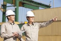 Male Chinese shipping industry workers pointing and writing at dock — Stock Photo