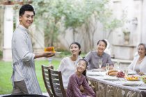 Chinese man serving grilled corn for family — Stock Photo